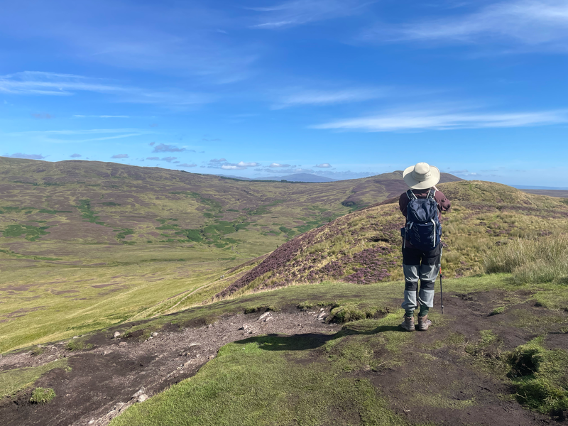 B with his back to us, looking at a panorama of mountains.
