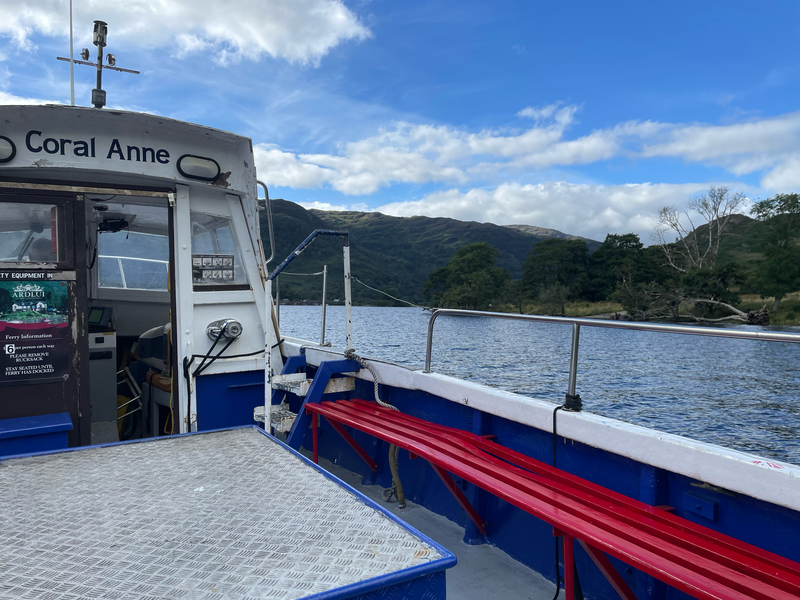 View over of a loch surrounded by mountains over the side of a boat called the Coral Anne.
