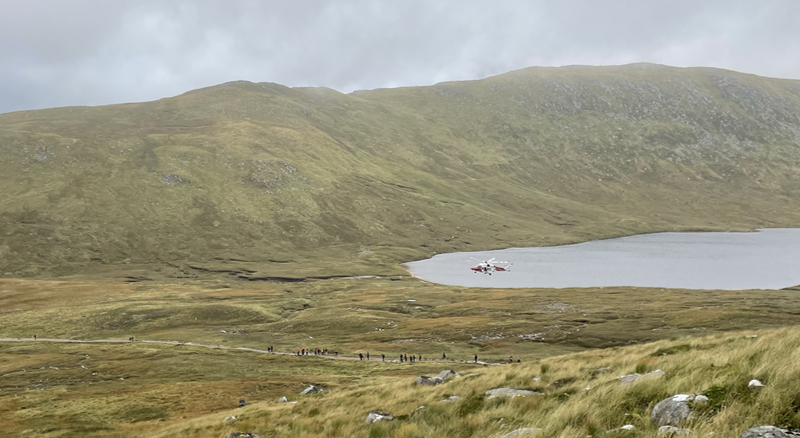 A helicopter hovering above a path full of walkers.