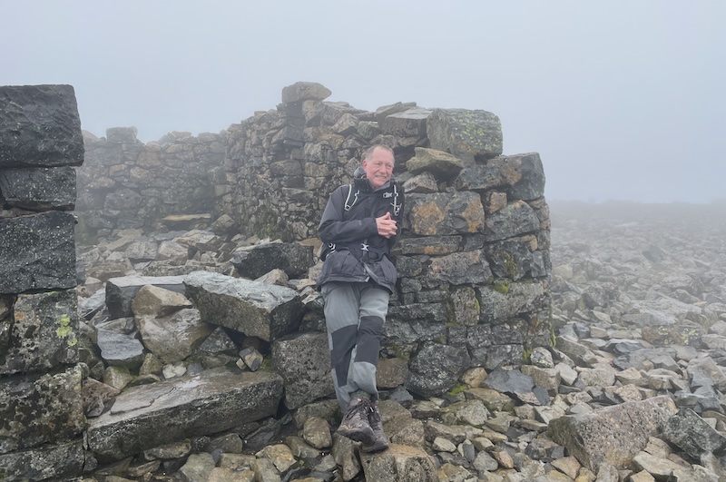 B. sitting on a ruined building in the rain.