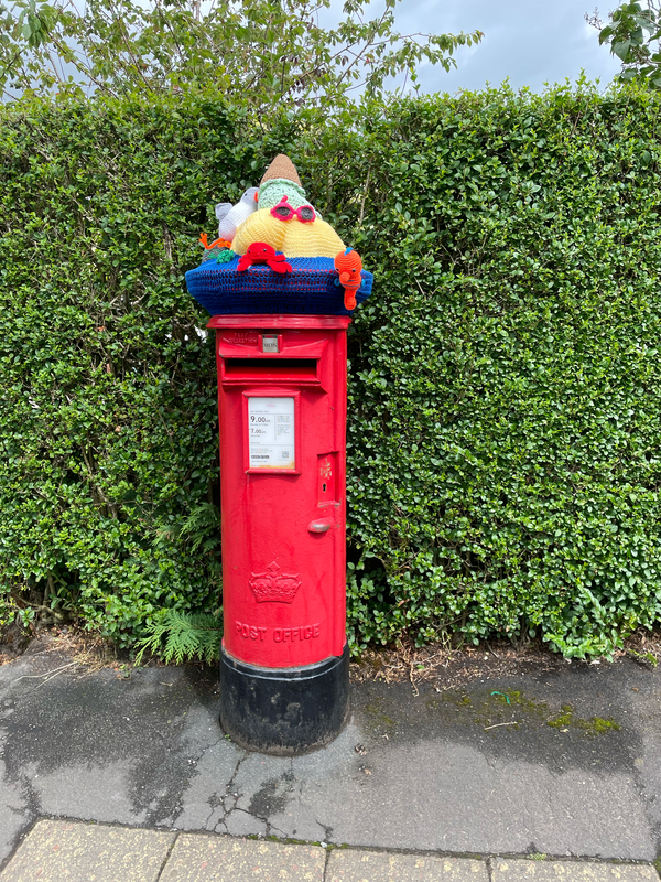 A yarn-bombed postbox with crocheted fish.