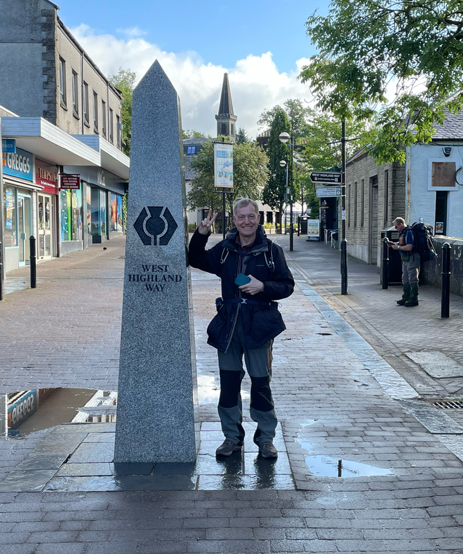 B. Standing next to the obelisk marking the start of the West Highland Way.