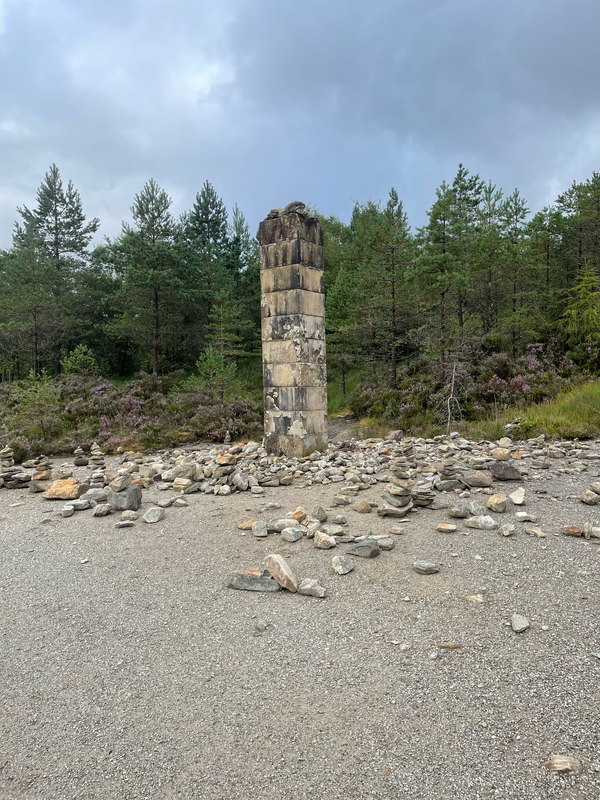 A tall upright stone pillar surrounded by small piles of rocks.