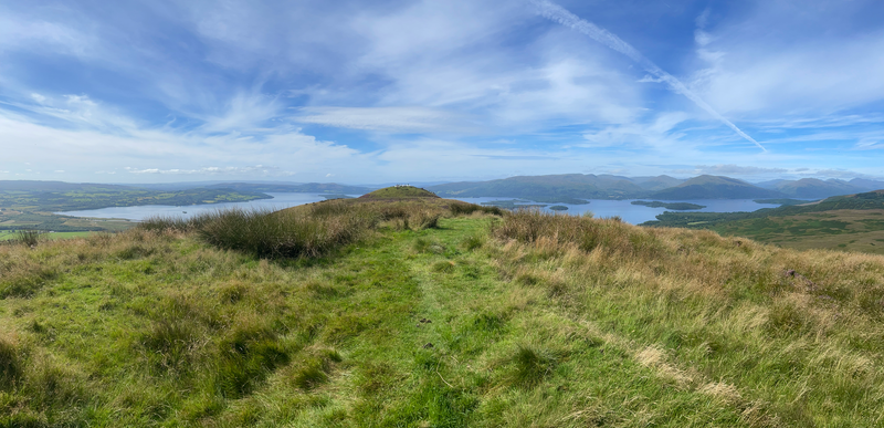 Blue sky, hill to the right, Loch Lomond below.