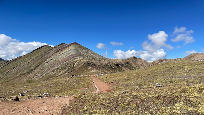 A view along a path towards a mountain striped in red, yellow and green.