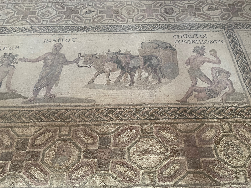 Half of a mosaic showing a man (Ikarios) leading oxen and then one man beating another labelled Oiprotoi Oinonpiontes.