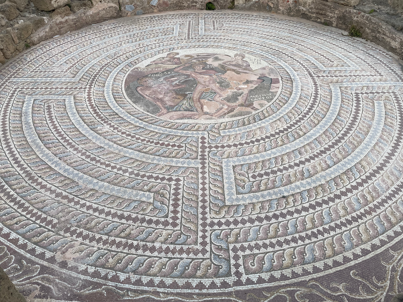 A circular mosaic with a zigzaging spiral design and an image of someone running in the centre.