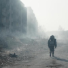 A figure with a backpack moves along a deserted burnt out street from Wendern 2053 from Dark.