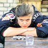 Ace leadning on a table with folded arms looking bored.