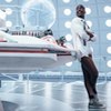 The fifteenth Doctor leaning against the Tardis console with no trousers on.