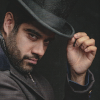 Dhawan Master touching his top hat looking at the camera.