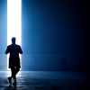 Silhouette of Dhawan master standing before slightly open warehouse doors.