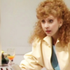 Mel from Doctor Who.  Seated at a table.  Seen from waist up in a cream top.