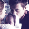 Amy holding Baby River while Rory kisses her.