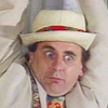 The seventh Doctor. White coat, head and shoudlers, hangind from something.