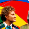 The Sixth Doctor -  head and shoulders with a multi-coloured umbrella