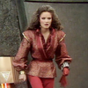 Kate O'Mara as the Rani from the hips upwards, striding forwards in her red outfit.