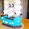Blue iced cake in the shape of a pirate ship.