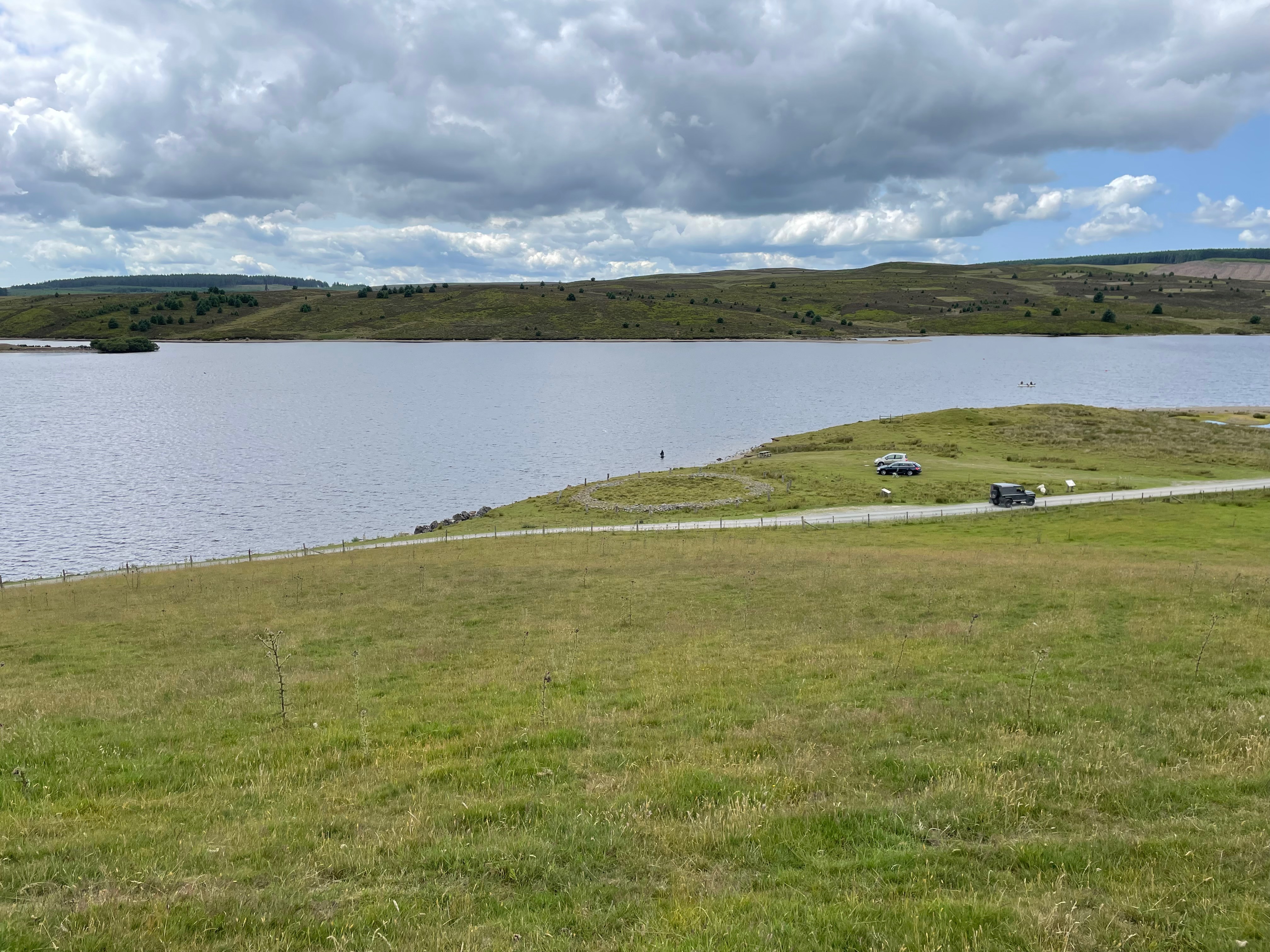 Hills and a lake.  This side of the lake a circle can be seen on the ground.