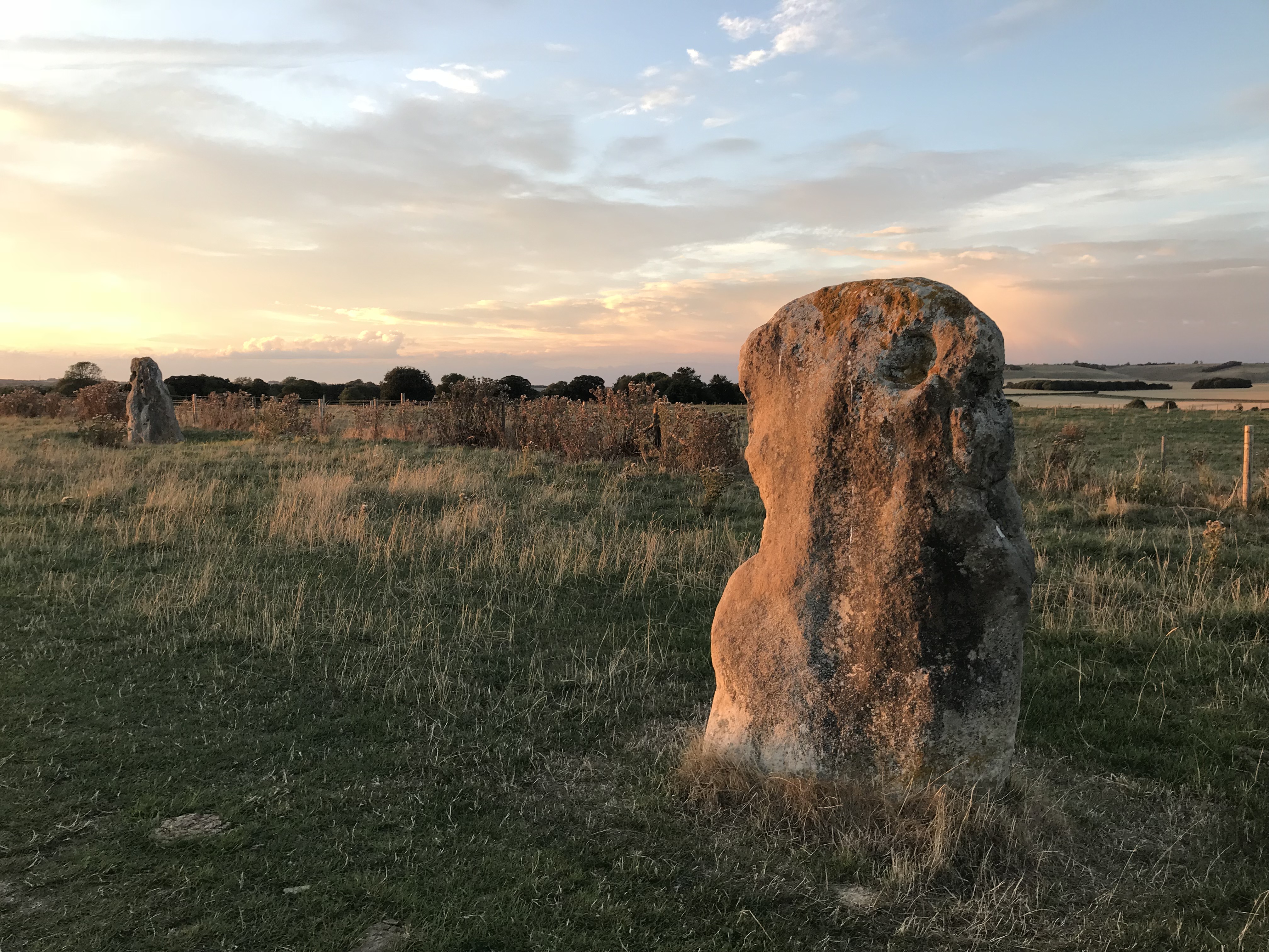 A low standing stone at sunset, another visible some way from it.
