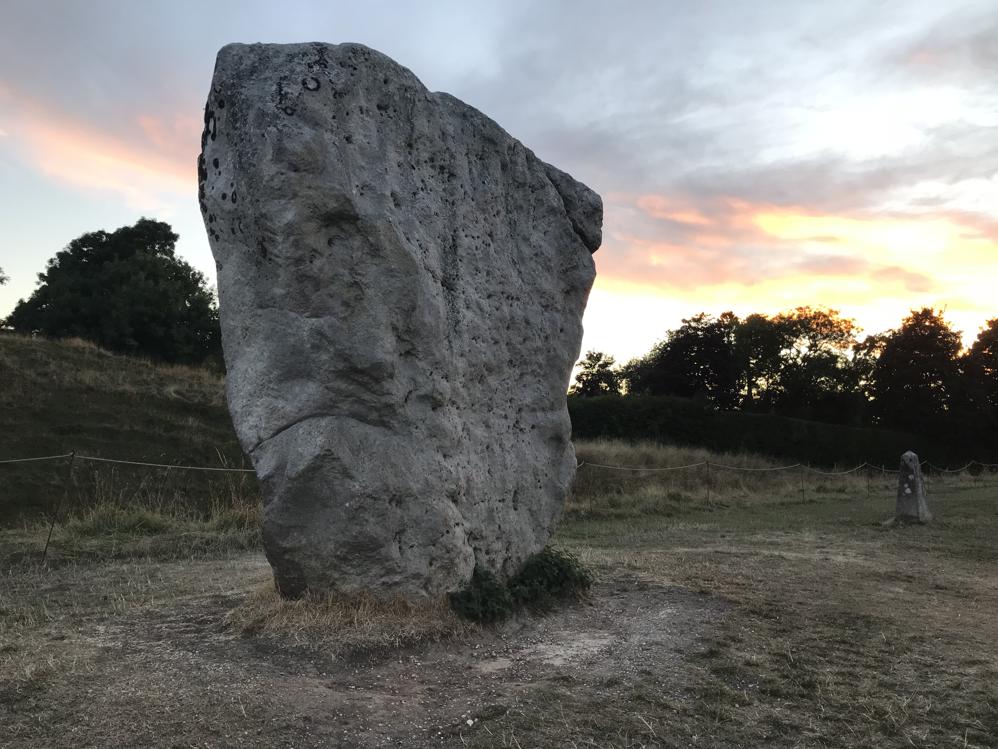 Large standing stone, close to the bank, with setting sun behind