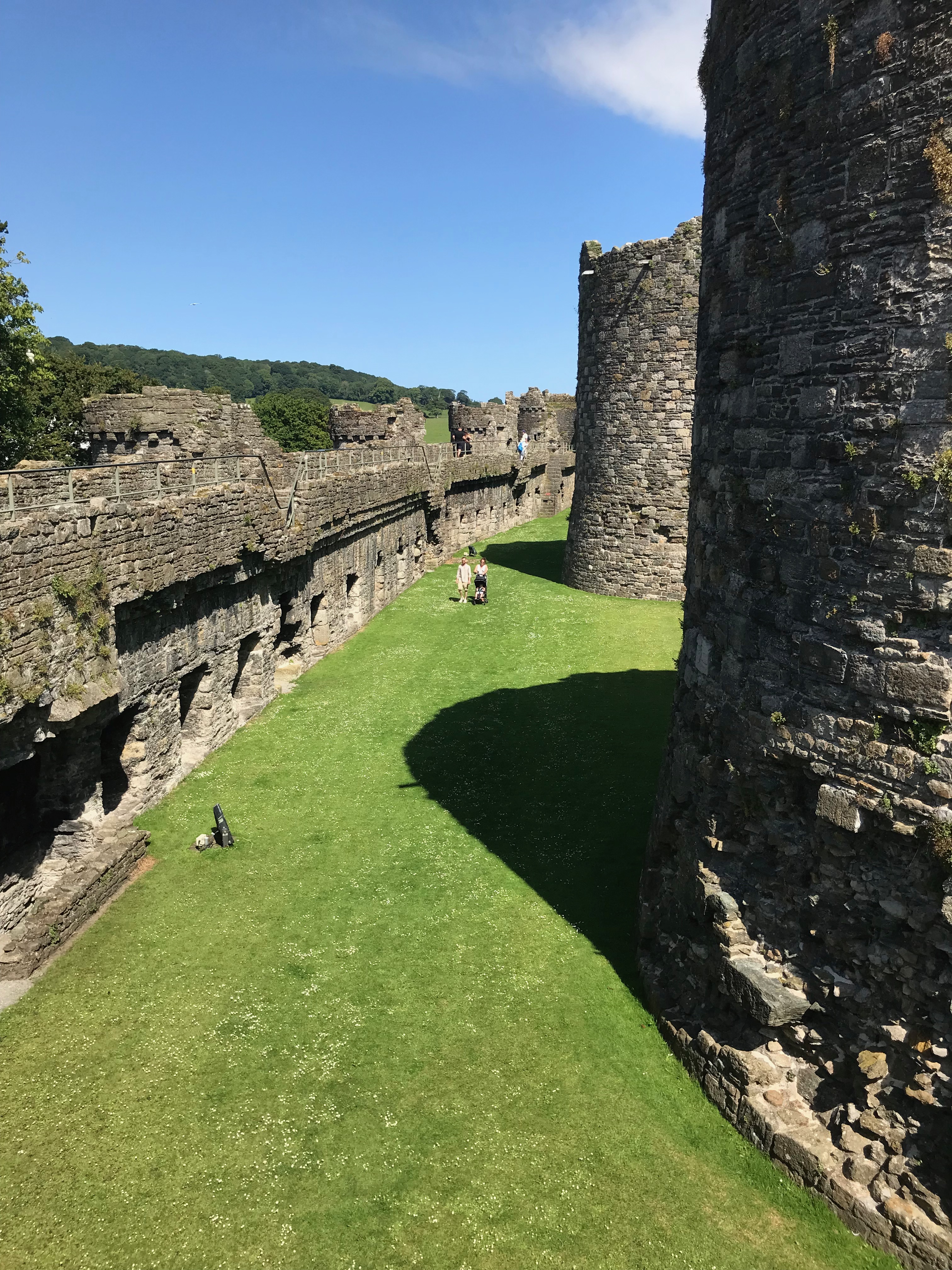 View down between the outer and inner walls of a castle.  Two turrets are visible.