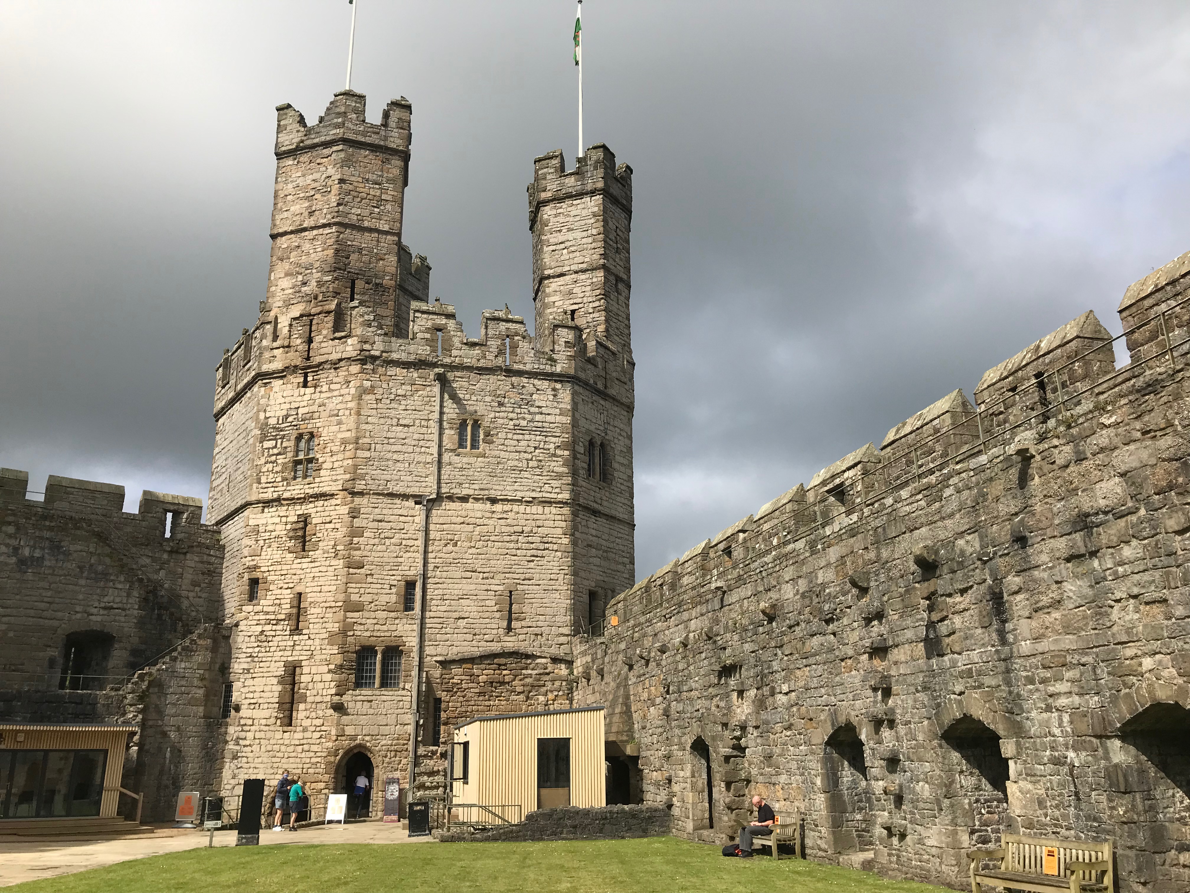 a tower at Caernafon Castle with three smaller towers on top of it, and the castle walls either side.