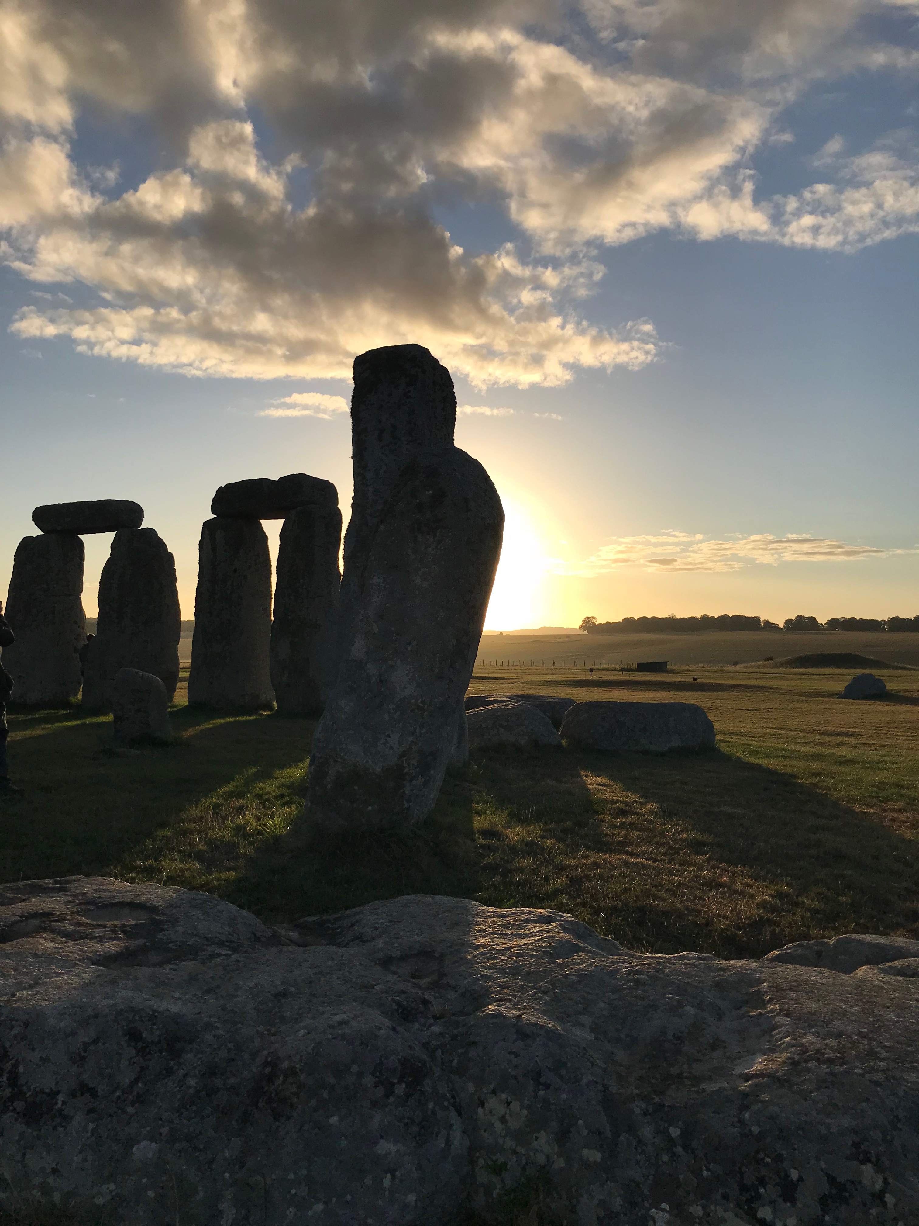 Stonehenge at Sunrise.  Two arches and a lone stone silhouetted against the rising sun.