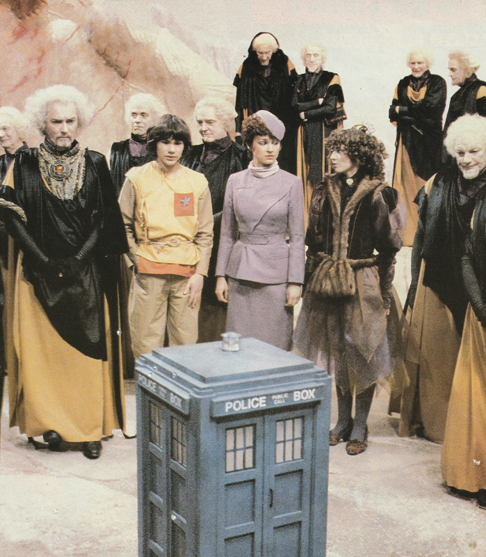 A scene from Logopolis.  Adric, Tegan, Nyssa and various logopolitans stand around a small Tardis.